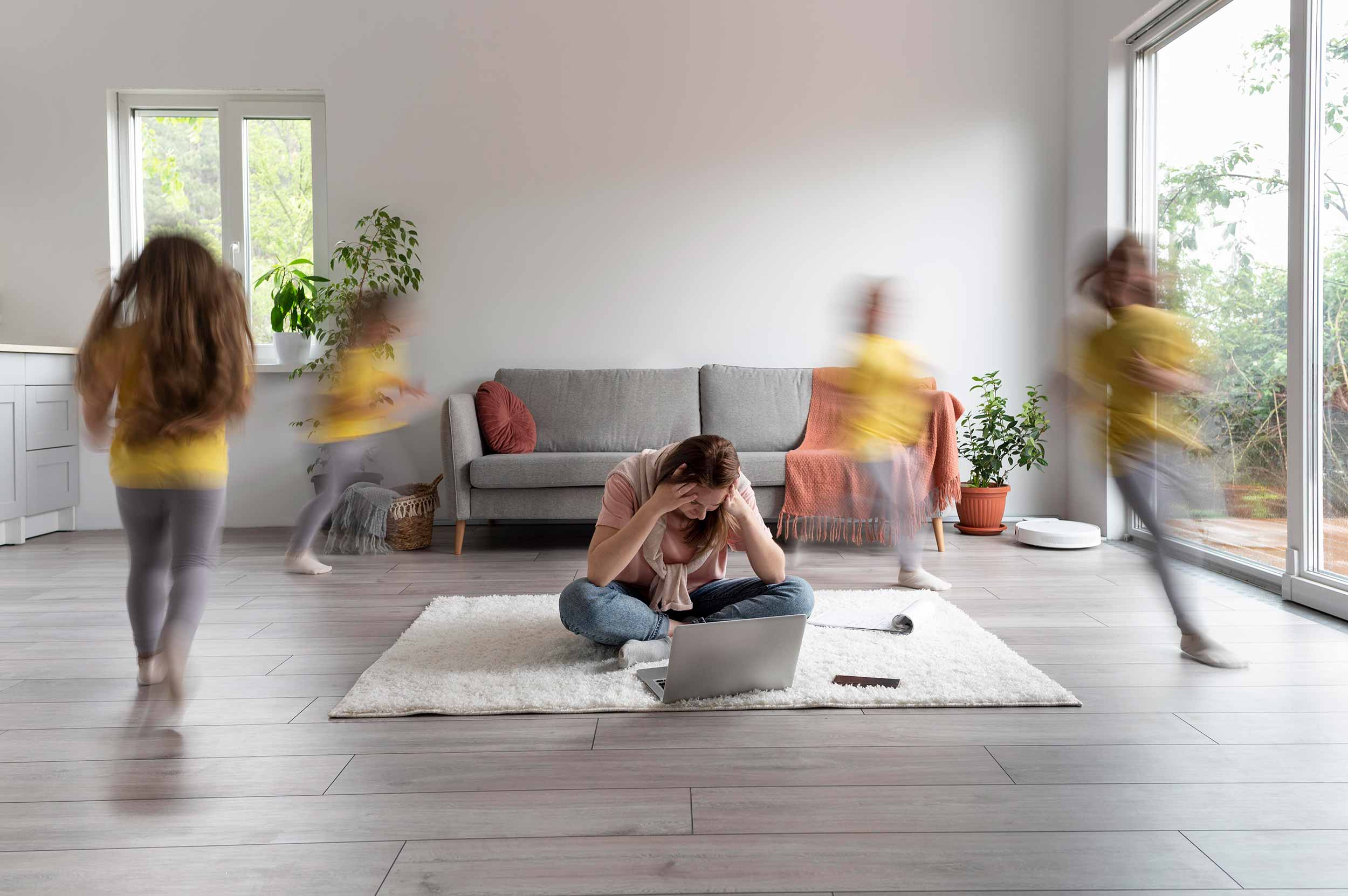 Person som sitter på golvet med barn som springer runt, högt ljud hemma